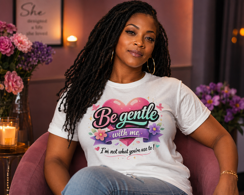 Woman wearing a white t-shirt with a colorful message sitting in a room with flowers and candles.