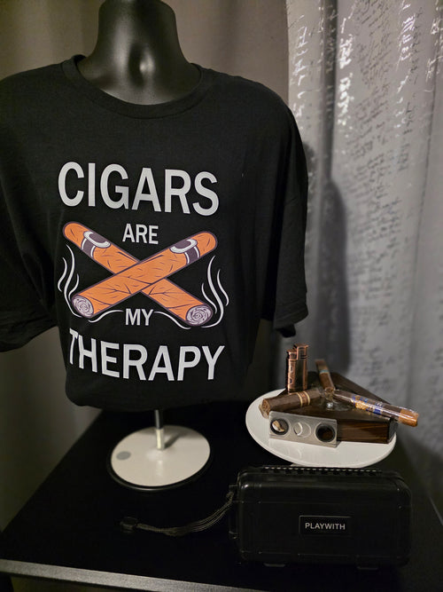 Black t-shirt with 'Cigars are my therapy' design on a mannequin, next to a small table with cigars and a humidor.