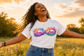 Woman wearing a 'Lead with Love' t-shirt in a field at sunset